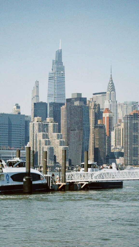View of New York City skyline featuring iconic skyscrapers and waterfront docks.